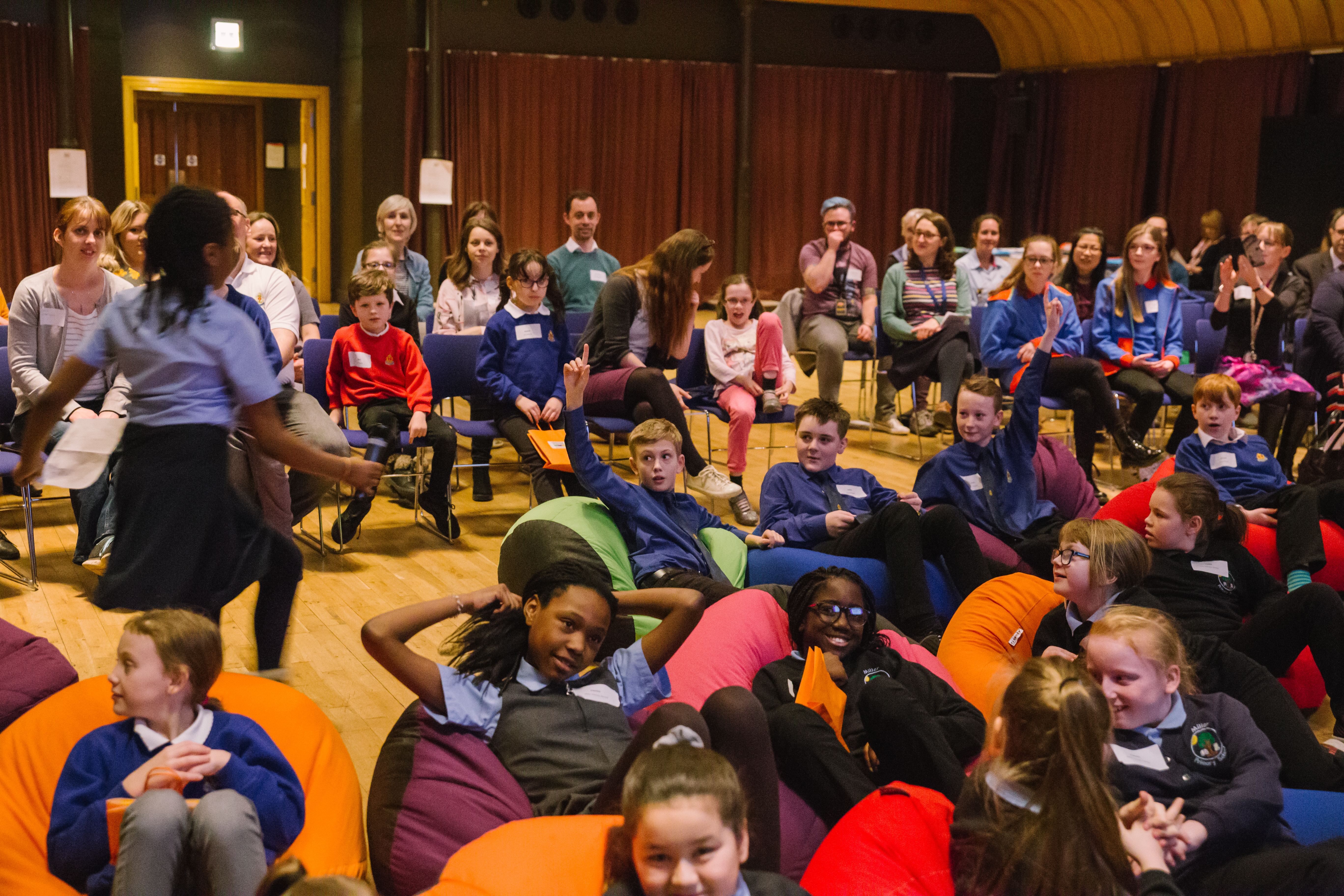 Young people sit in a hall, some on beanbags some on chairs