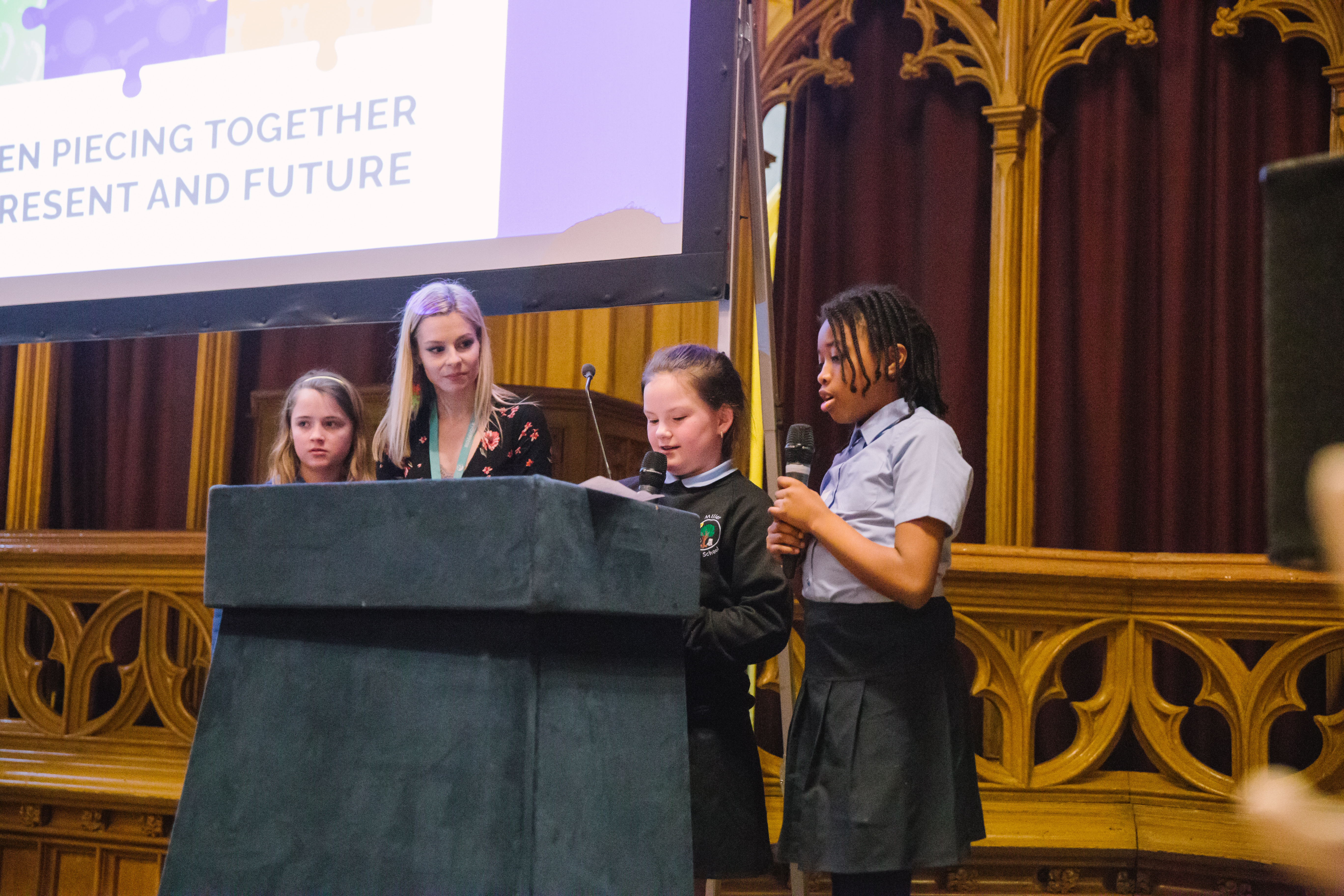 Young people stand at a podium, speaking into microphones