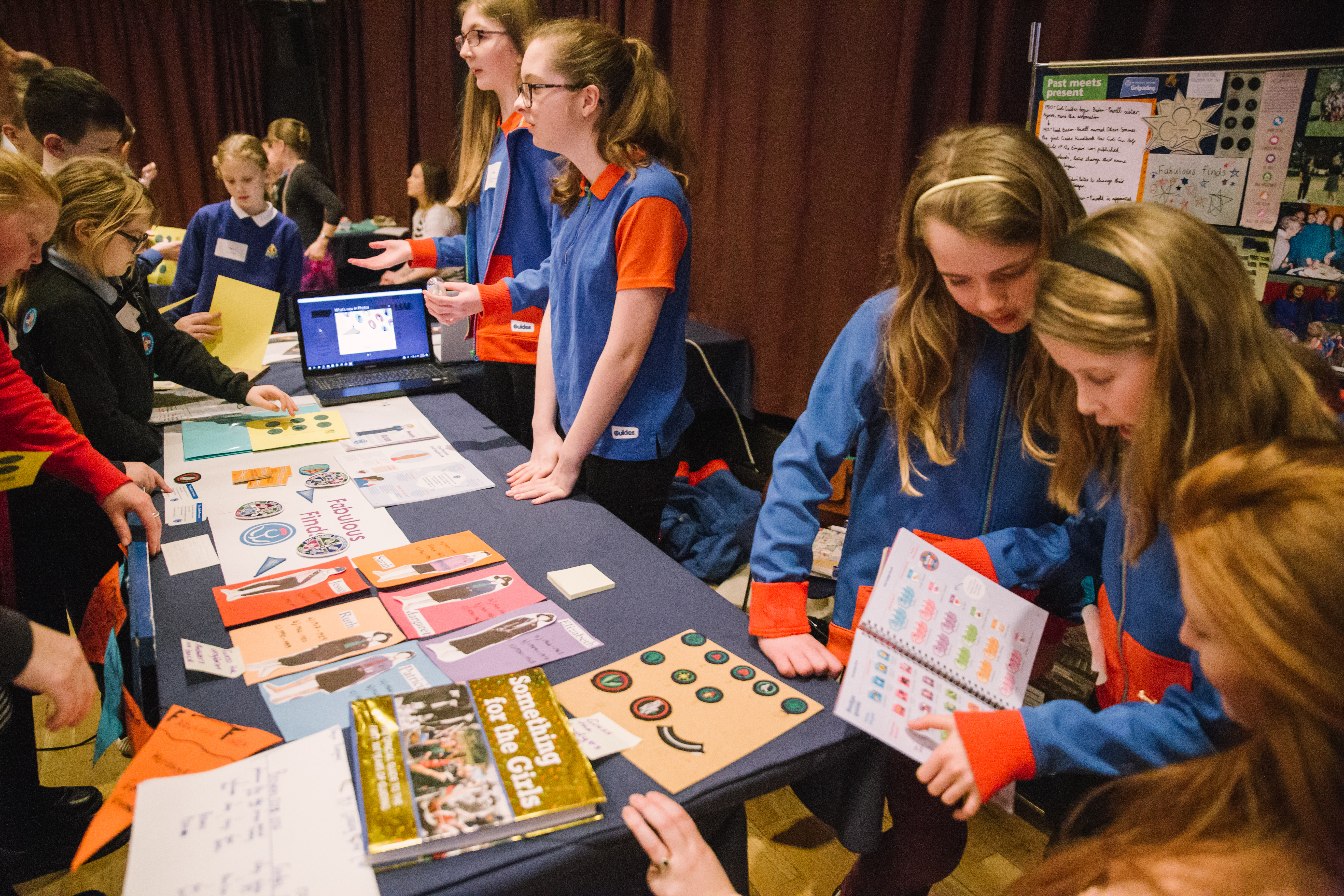 Young people at a colourful table, looking at books and talking