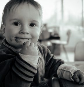 Black and white photo of a toddler eating a snack