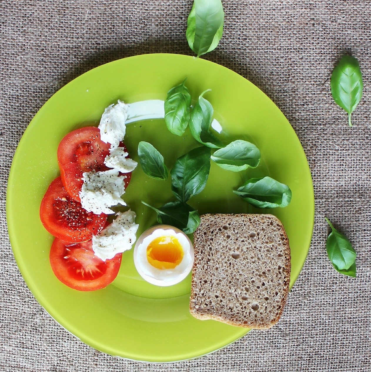 Green plate with egg, tomatoes, cheese and bread