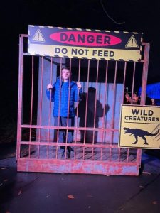 A young person behind bars next to signs that say Do Not Feed and Wild Creatures