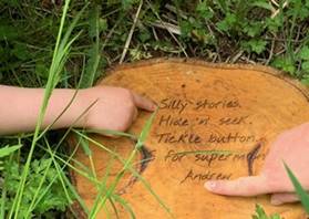 Two children's hands pointing at text on a piece of wood