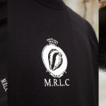 A black top with a white shell icon in the centre, and text below that reads M.R.L.C.