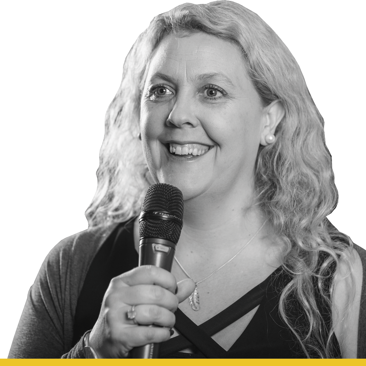 Black and white headshot of a woman with long blonde wavy hair. She is smiling and holding a microphone.