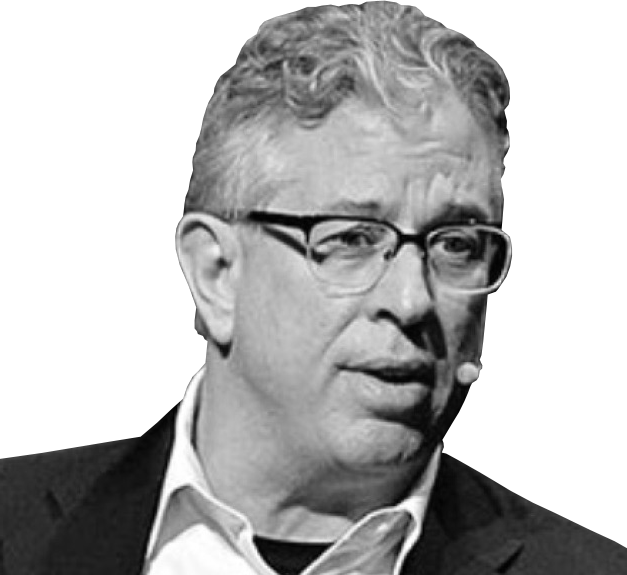 Black and white headshot of person with short curly light hair. They are mid-speaking and are wearing glasses, suit and a microphone, on a white background.