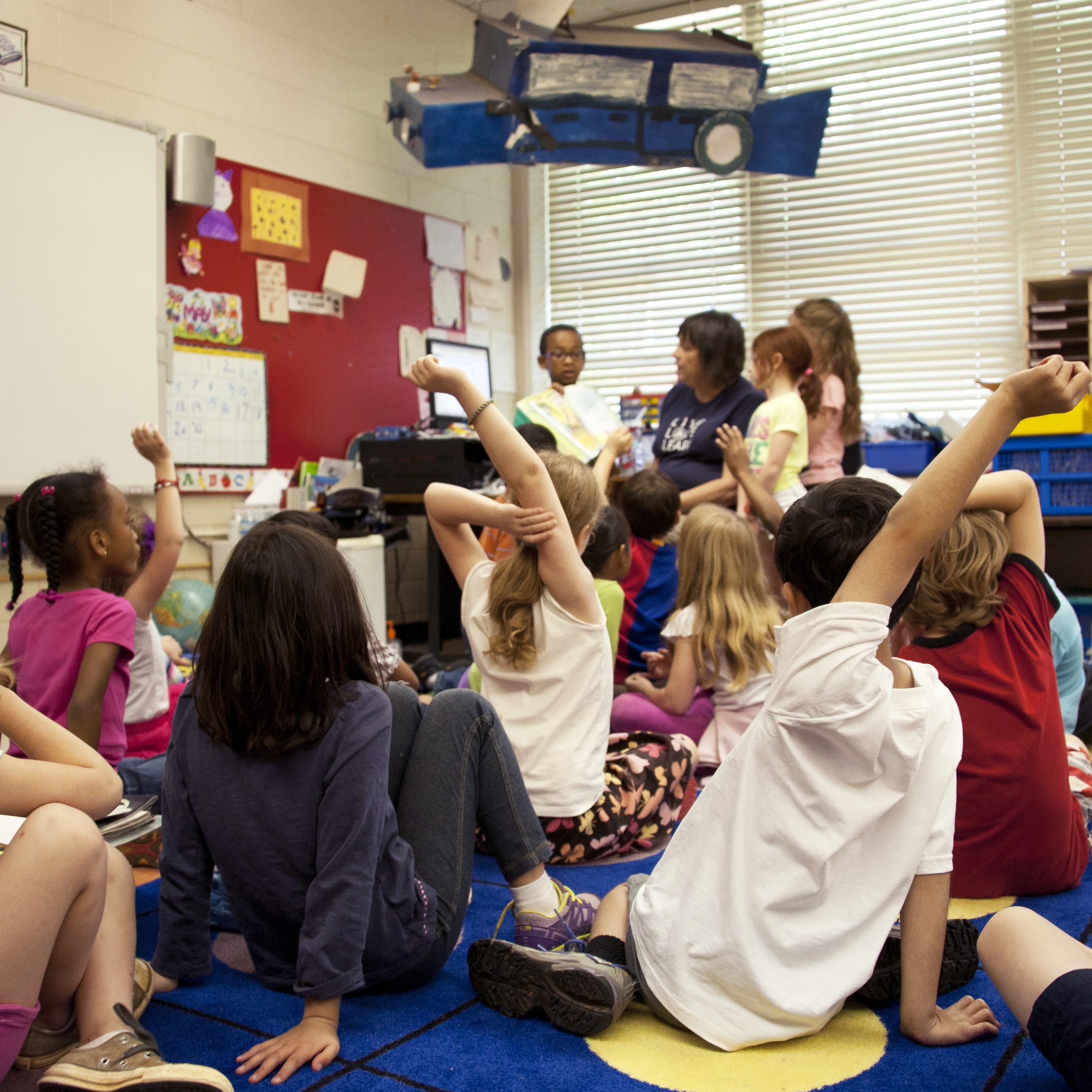Children with hands raised in school classroom