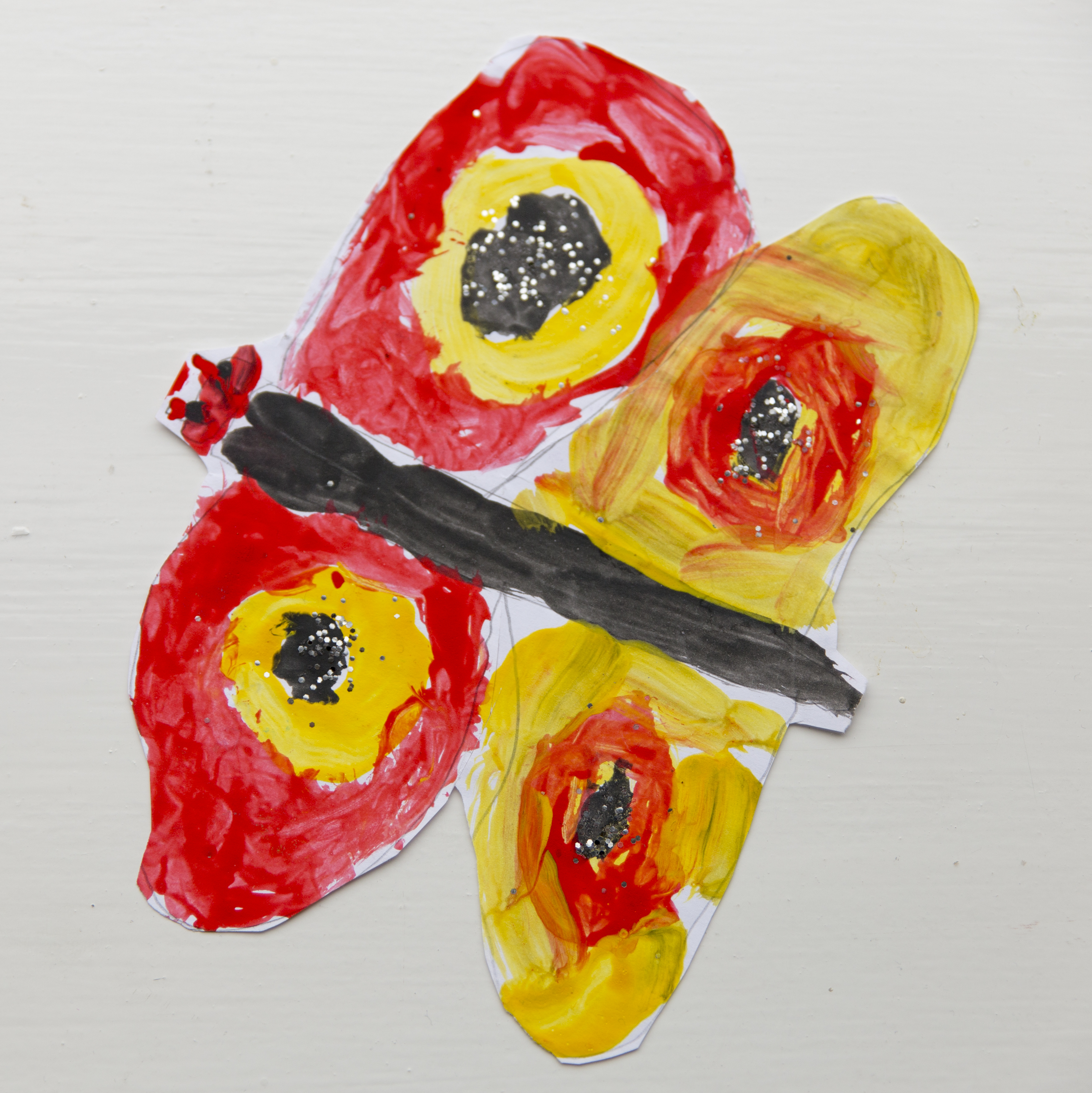 Child's finger painting of a butterfly using red, yellow and black paint
