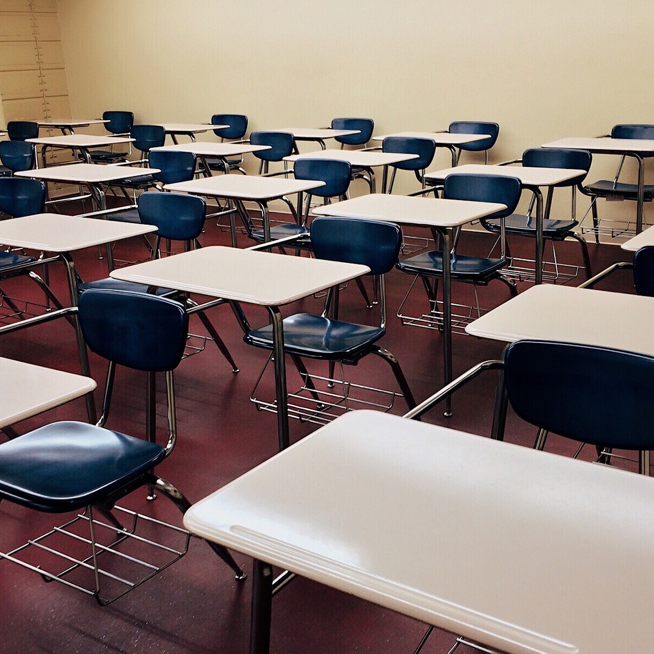 A photo of classroom desks and chairs lined up in rows, in an exam hall.
