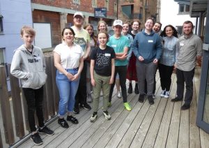 Photo of 12 young people and adults smiling at the camera. They are outside