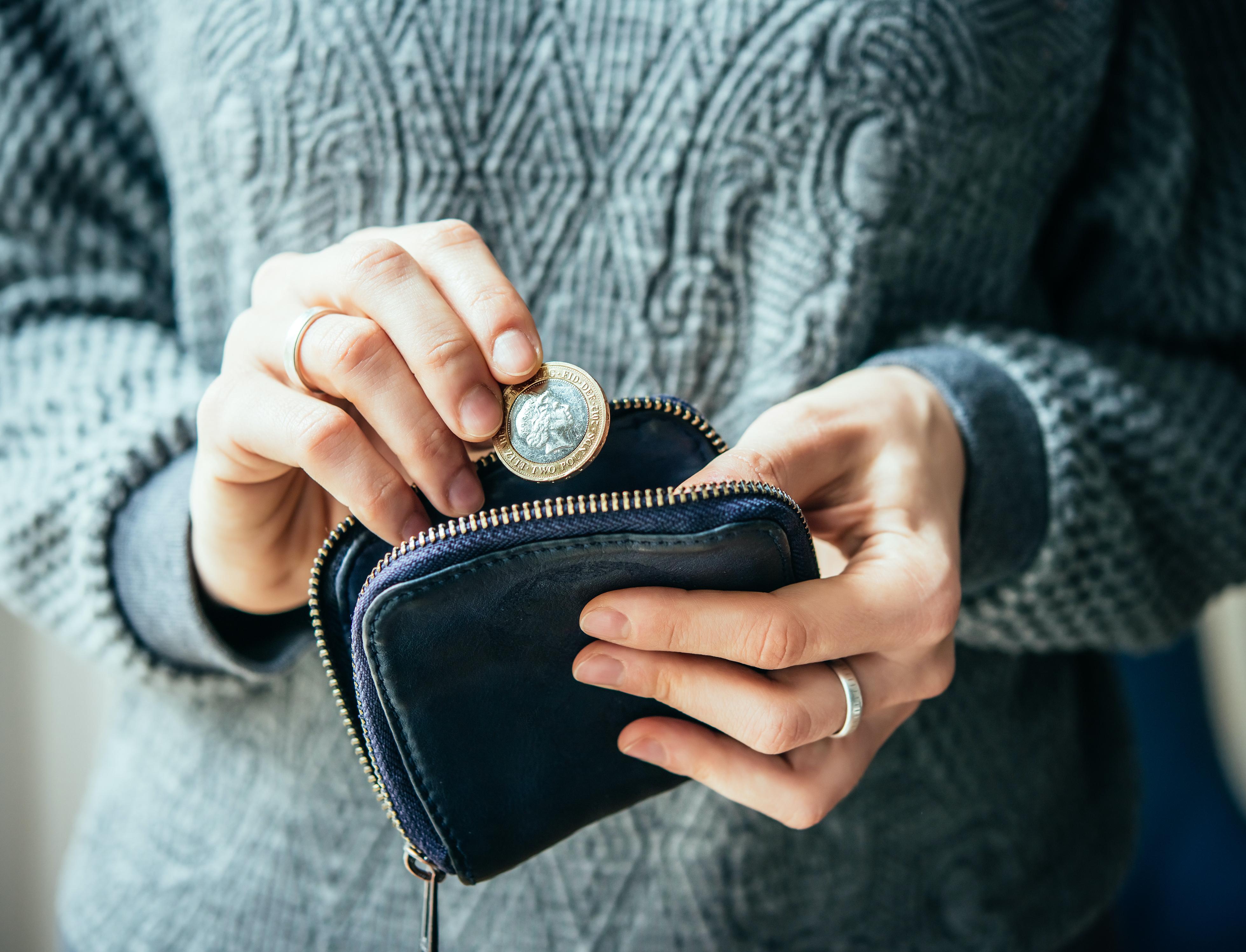 Hands holding british pound coin and small money pouch