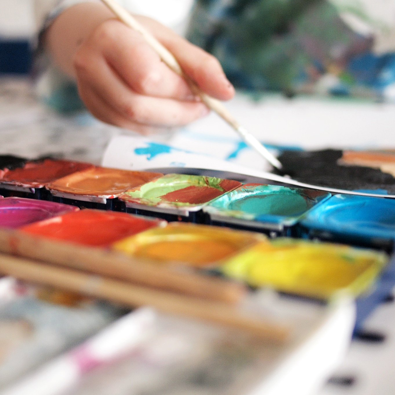 Paint palette with child's hand holding brush