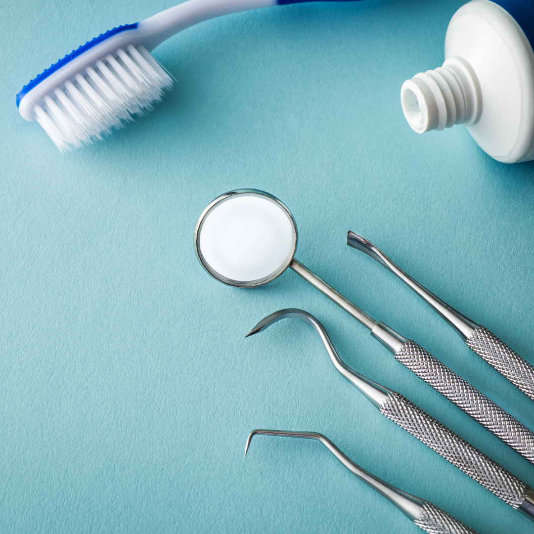 A selection on dental tools, including a toothbrush and oral mirror, rest on a blue background