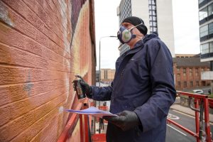 A graffiti artist works on a new outdoor mural