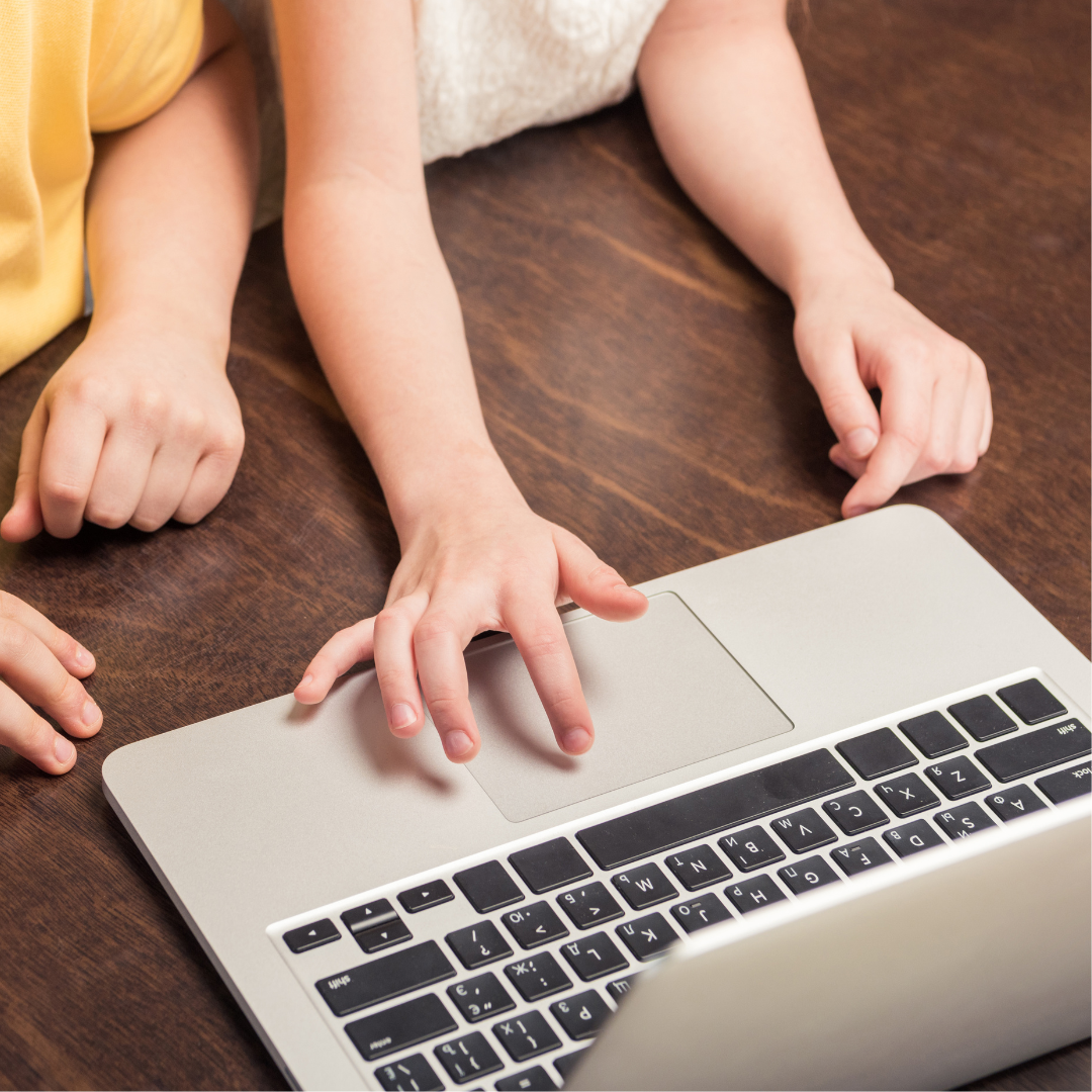 Two children's hands are shown using a laptop