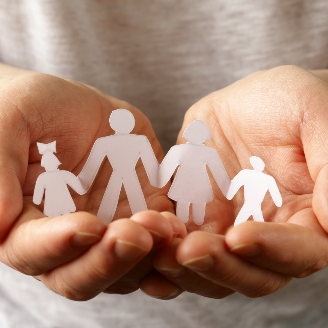 Cupped hands with a string of four white paper dolls in them. The dolls at each end are smaller