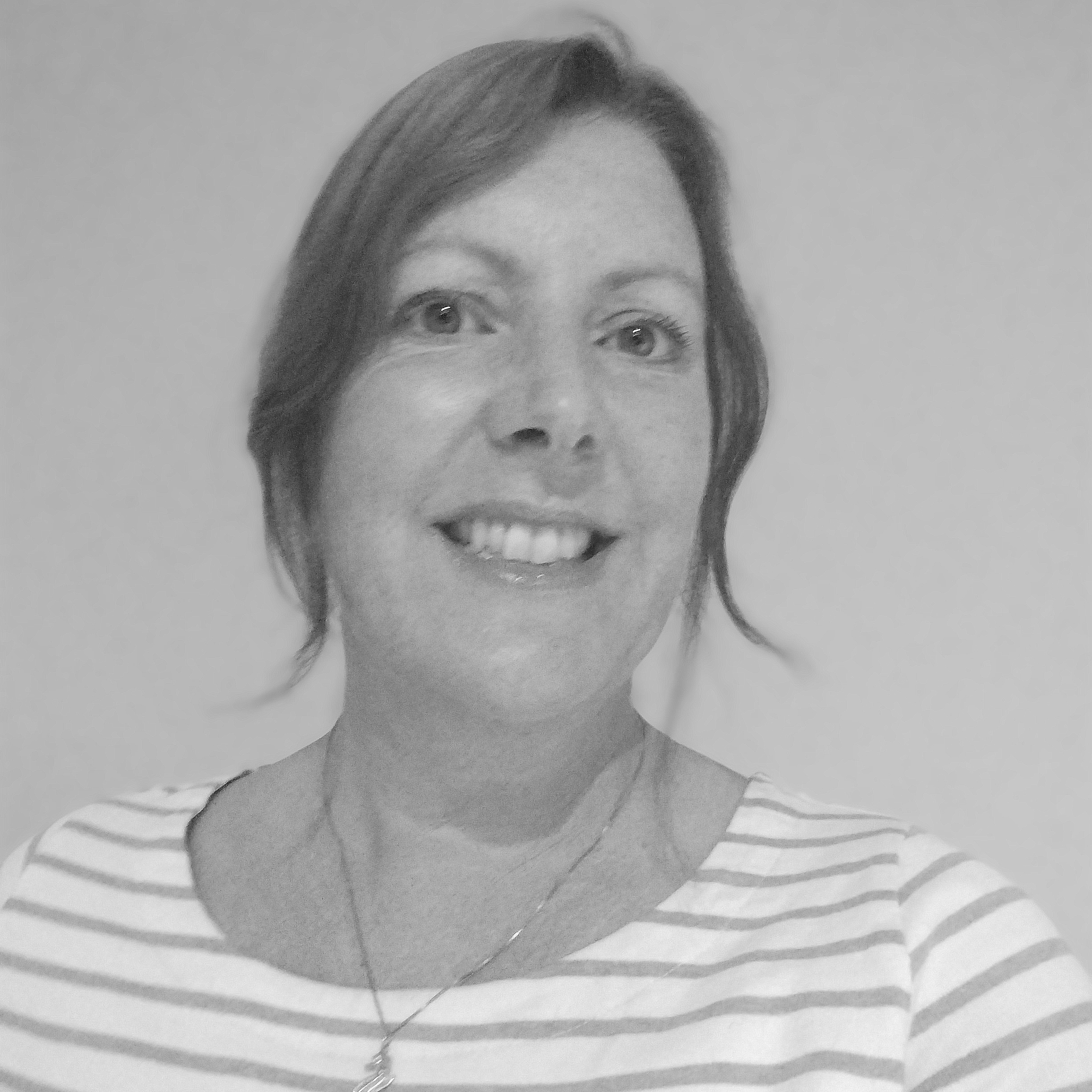 Black and white headshot of a smiling person in a white striped top and wearing a necklace