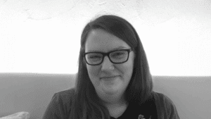 photo of person with long hair, smiling wearing glasses