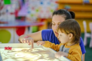 Creative early baby development. A mother teaches her child to draw with her fingers in the sand