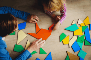 Young child and adult playing with large colourful mosaic pieces