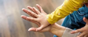Young child comparing the size of their hand with that of their mother