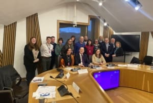 Image of a group of people sitting behind a large wooden desk